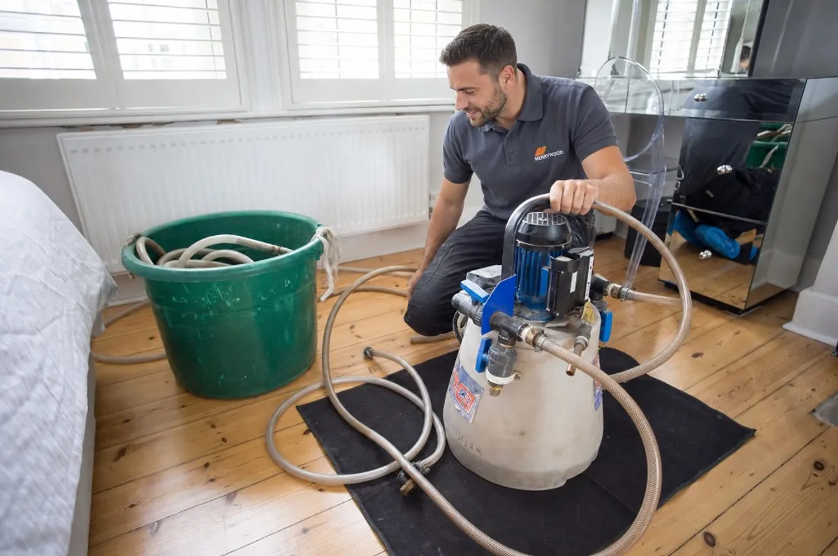 Local heating engineer power flushing a radiator system with professional equipment