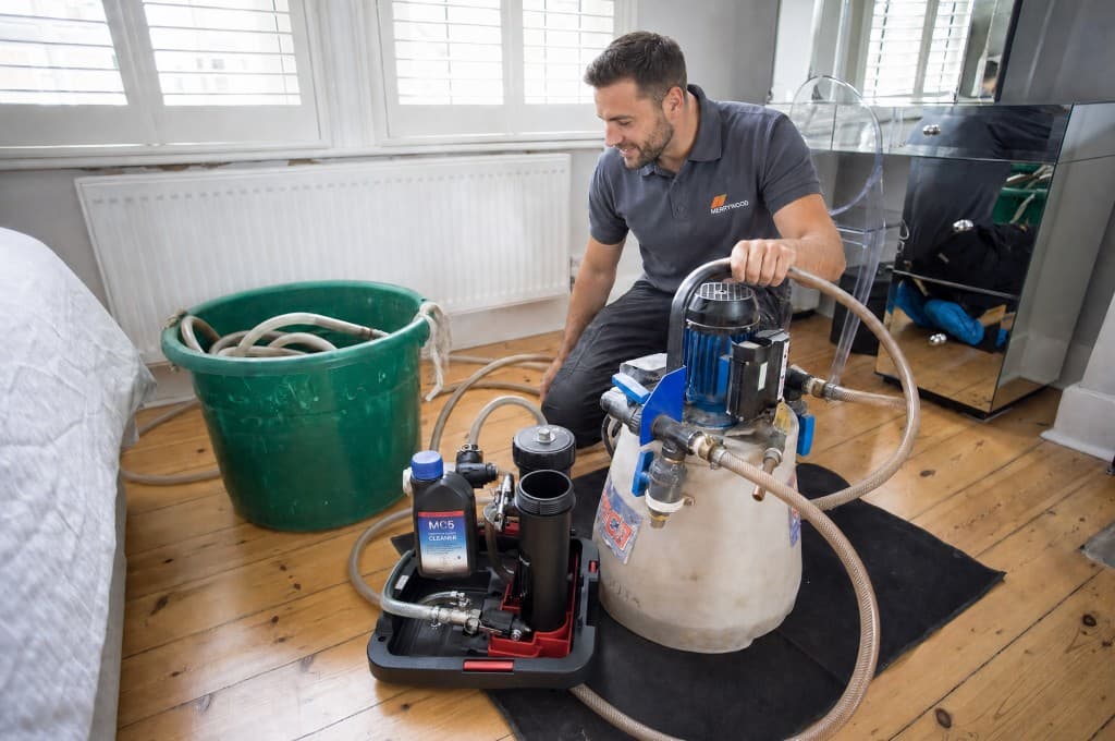 Power flush machine, magnetic filter and system cleaner set up by an engineer beside a radiator